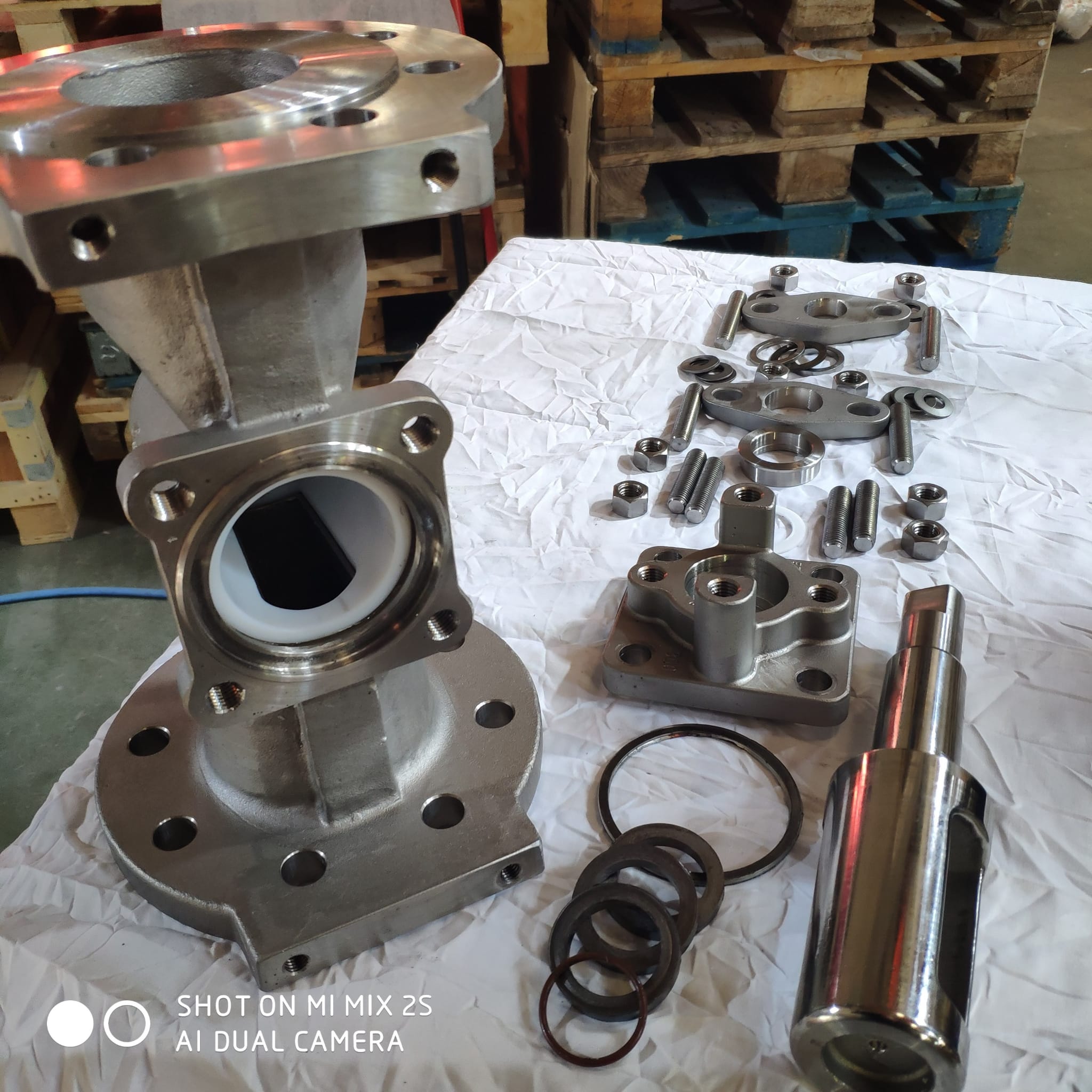 Disassembled stainless steel plug valve body showing the white PTFE-protected internal flow path